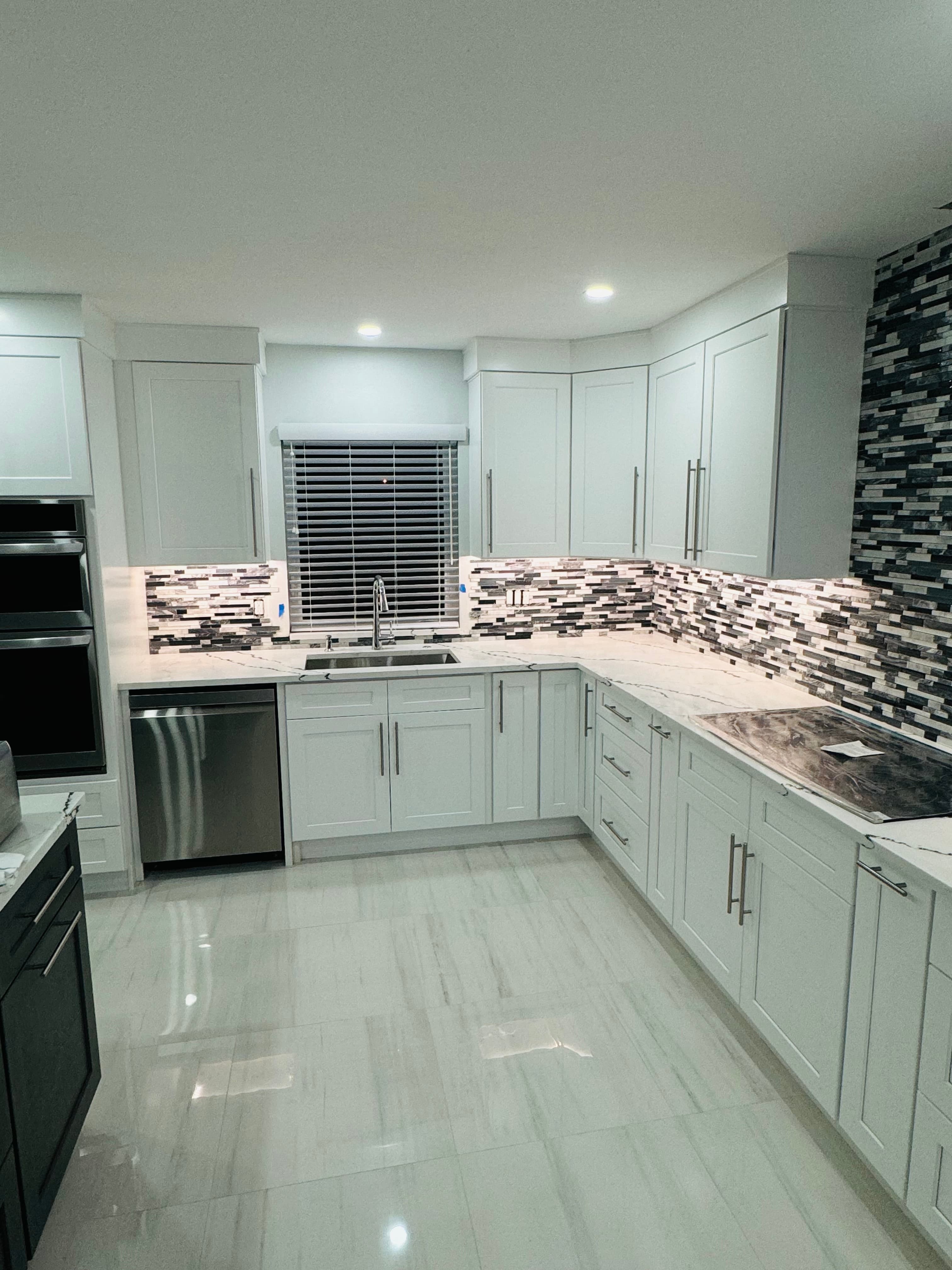 White kitchen with a mosaic tile backsplash and polished large-format tile floor
