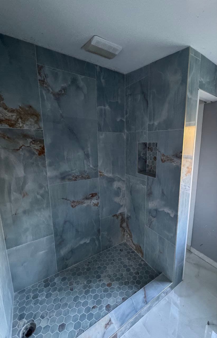 Bathroom walk-in shower with blue marble-look tile and a recessed niche