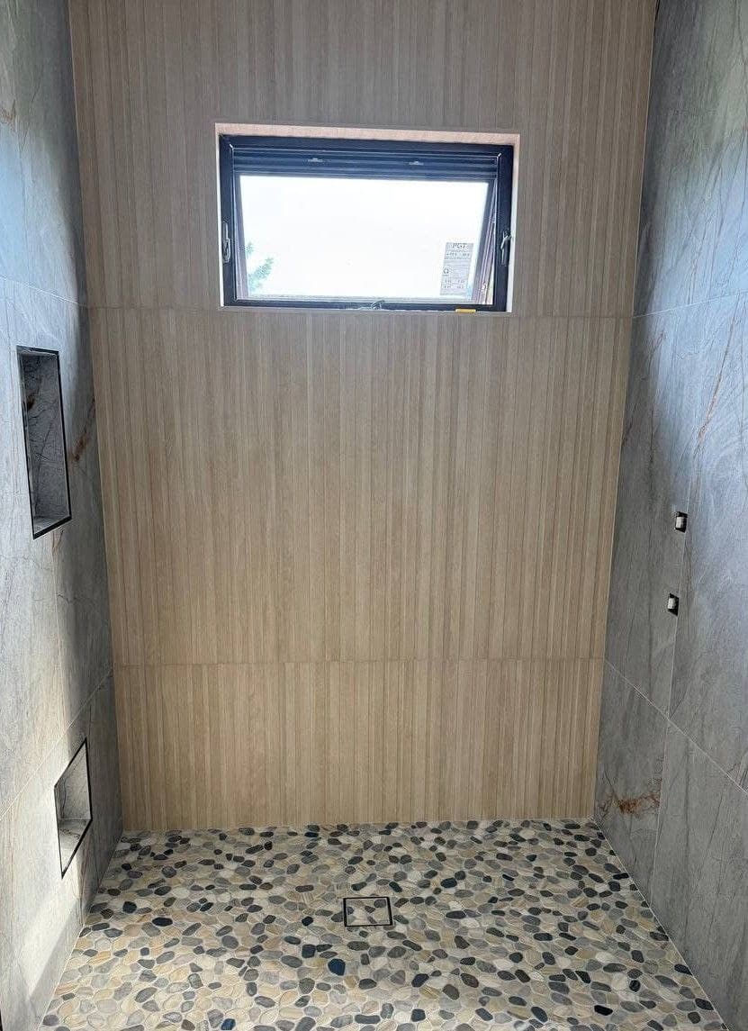 Bathroom walk-in shower with large-format wall tile and a pebble mosaic floor